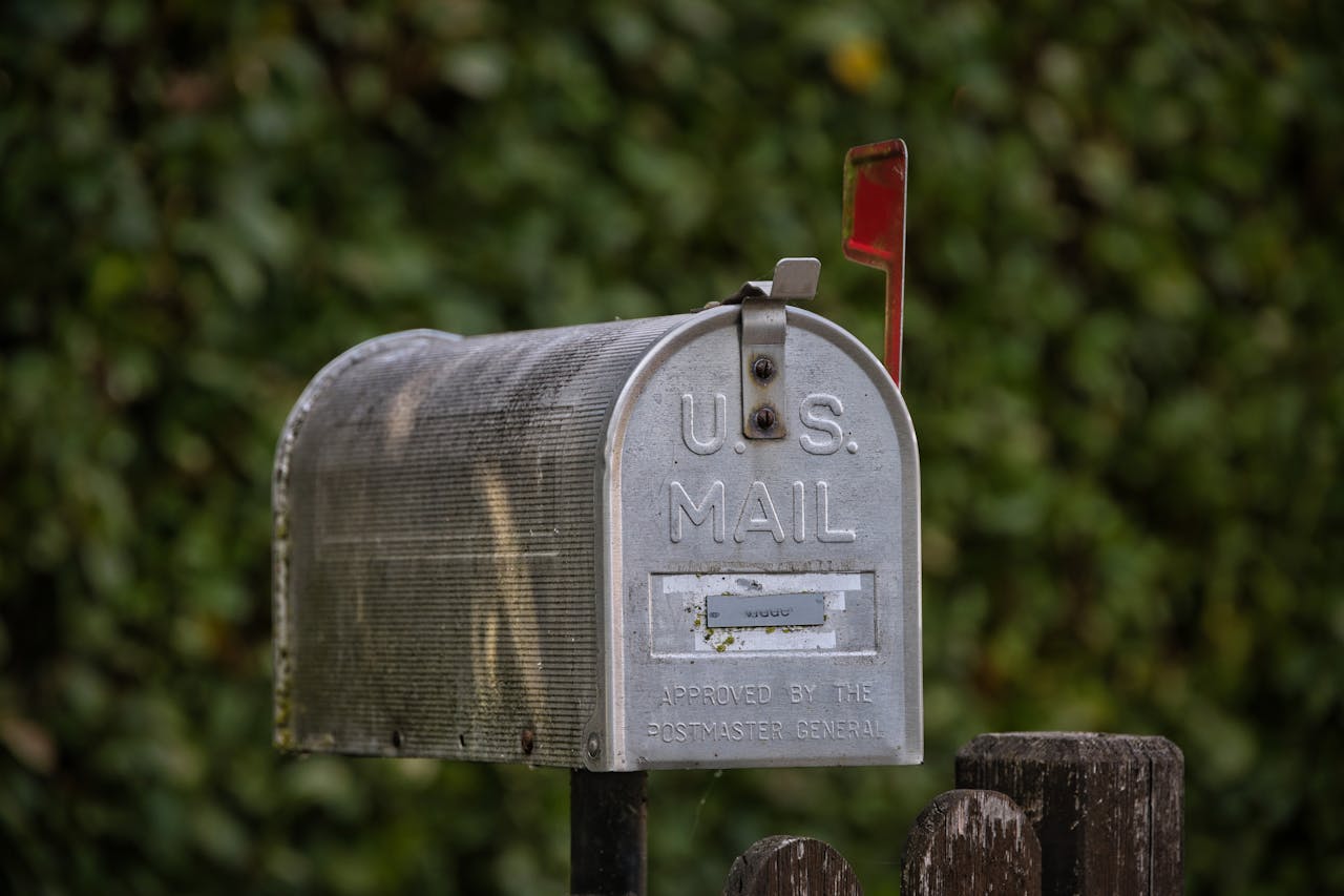 home-services-01 A traditional U.S. mailbox with red flag against a lush green blurred background.