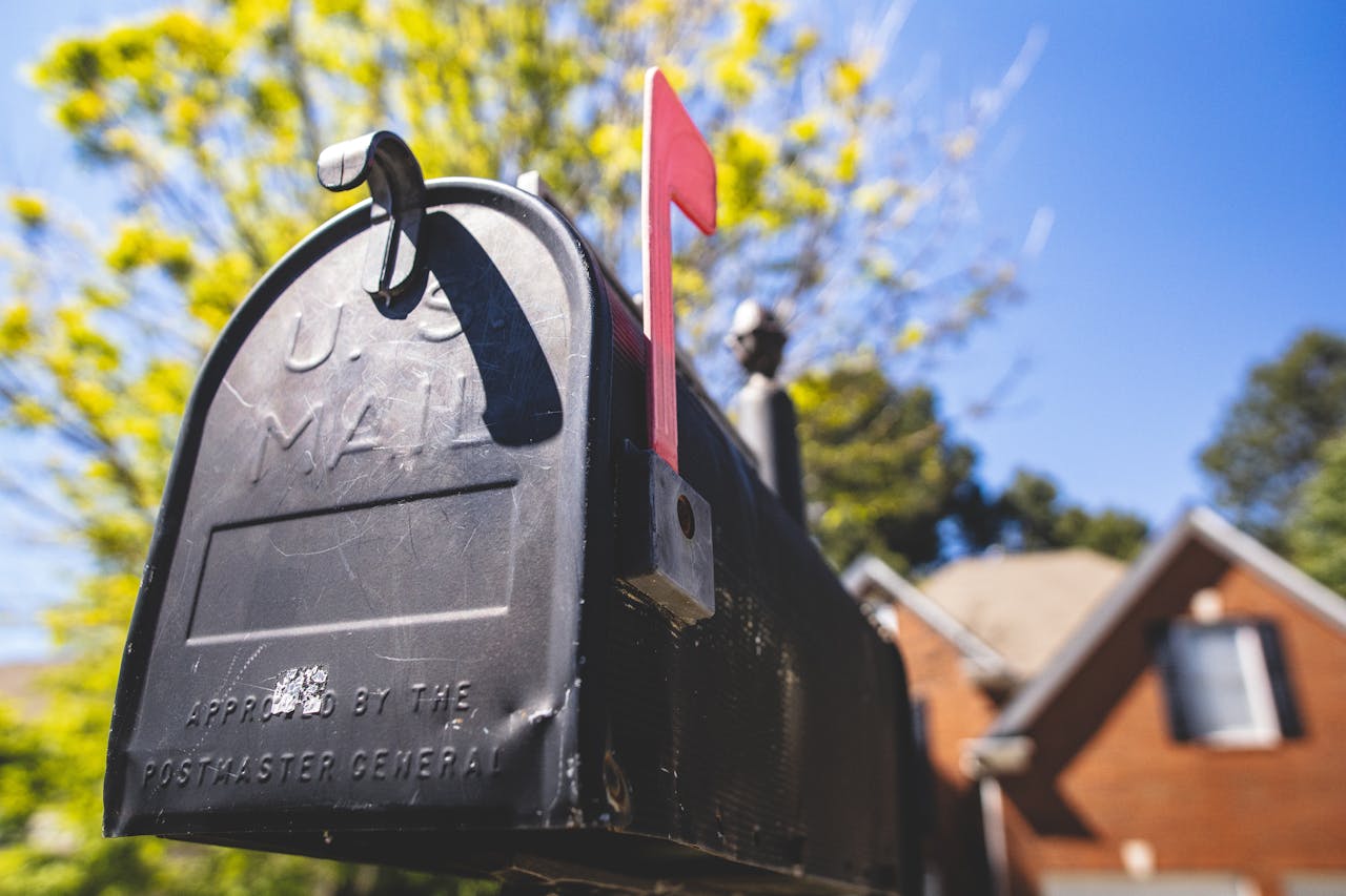 home-services-03 Close-up of a traditional US mailbox with a red flag in a sunny neighborhood.